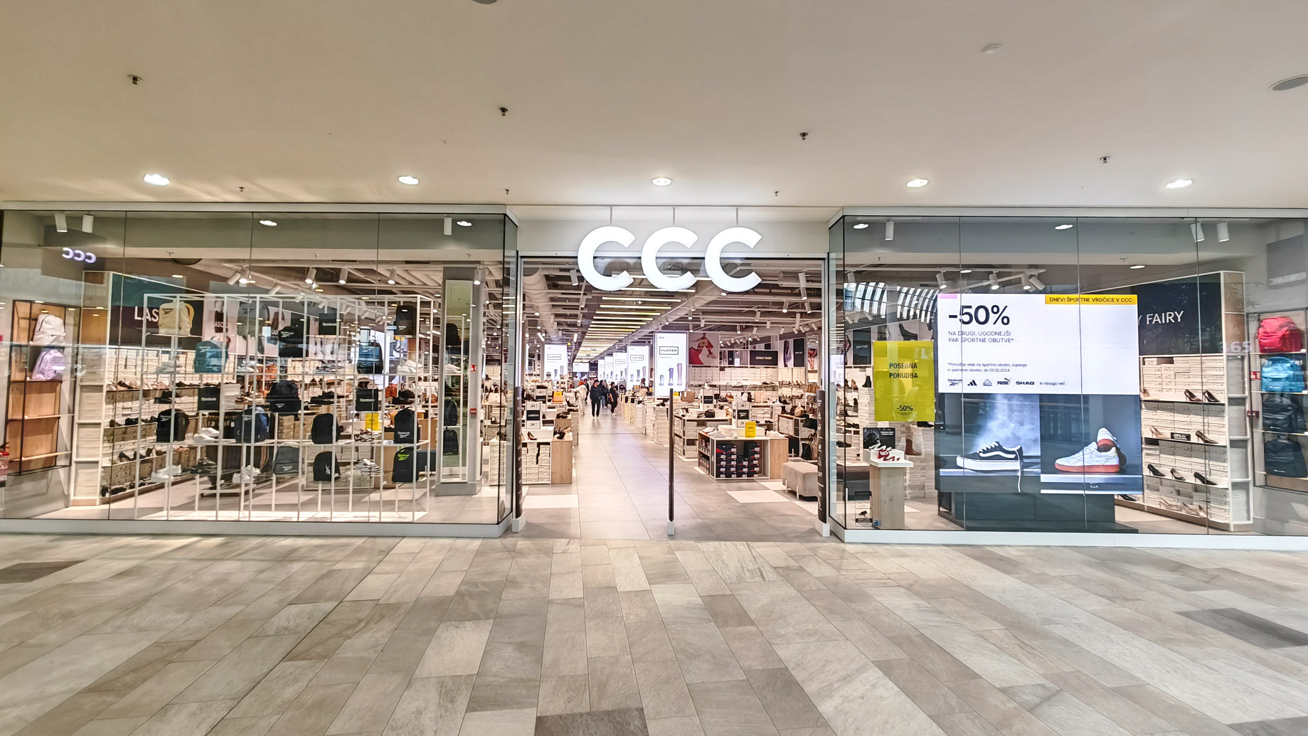 A storefront with the letters "CCC" prominently displayed, showcasing various shoes and bags inside a well-lit shopping area.