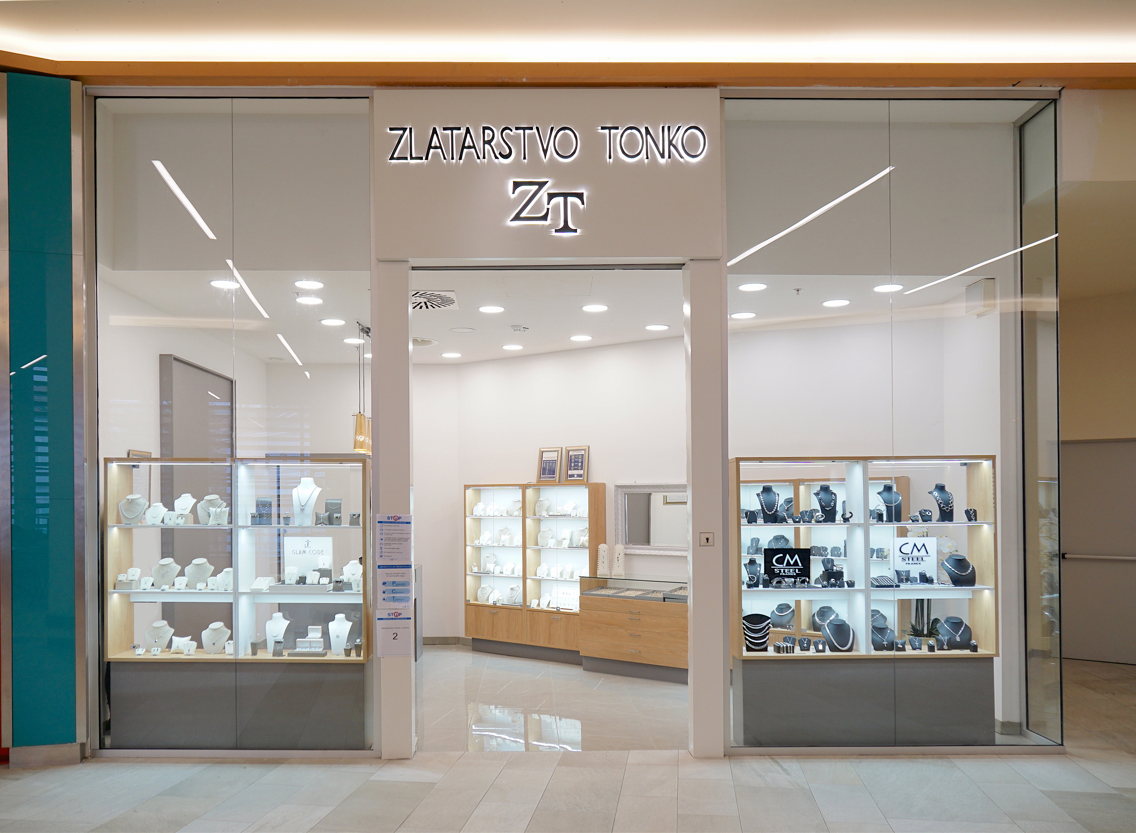 A jewelry store entrance featuring glass displays showcasing various jewelry pieces, with the name "Zlatarstvo Tonko" prominently displayed.