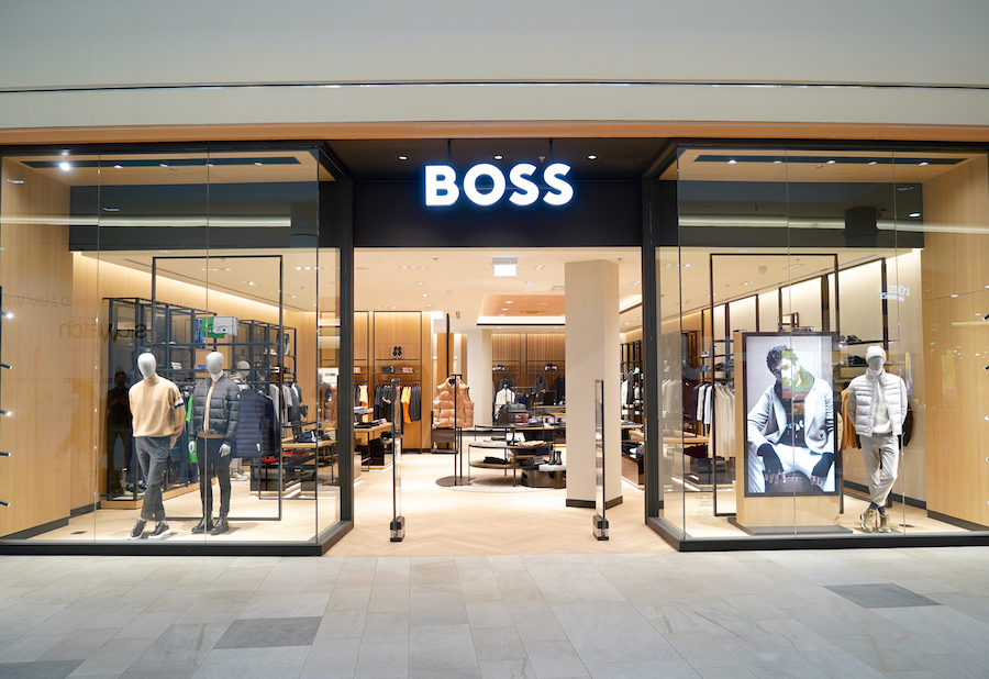 A modern clothing store entrance featuring mannequins in stylish outfits and a large "BOSS" sign.