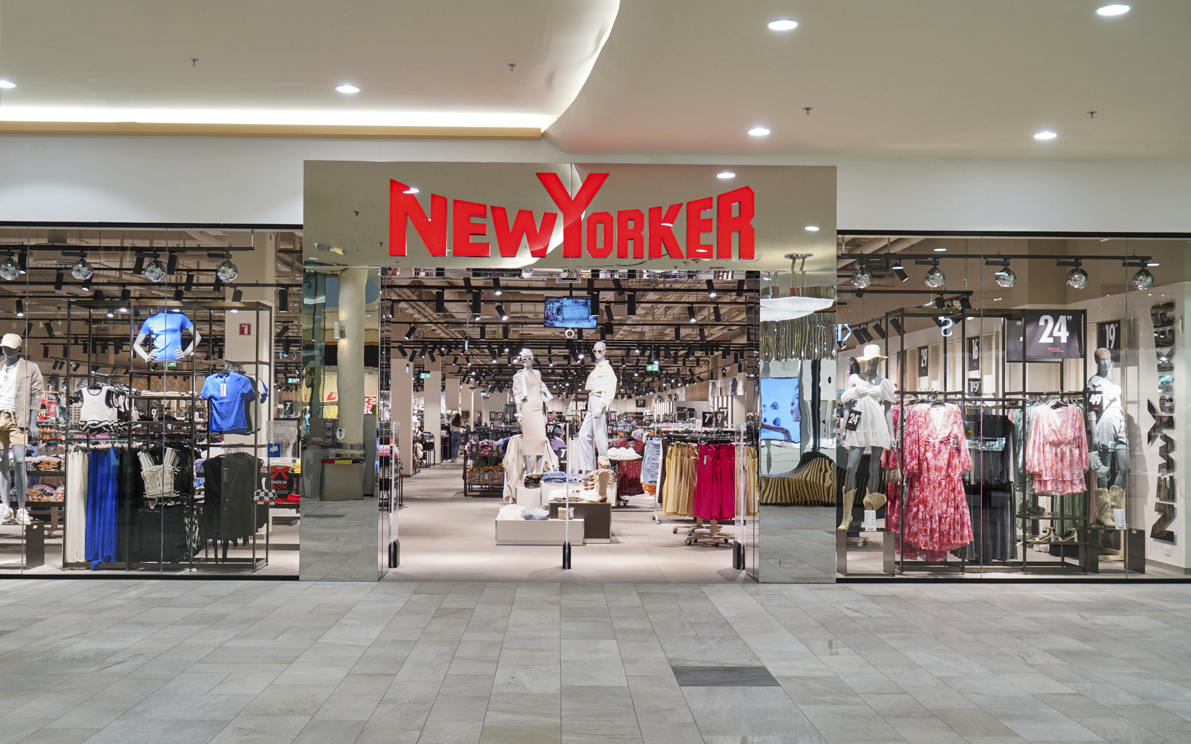 A storefront of "NEW YORKER" featuring mannequins and clothing displays inside a modern shopping mall.