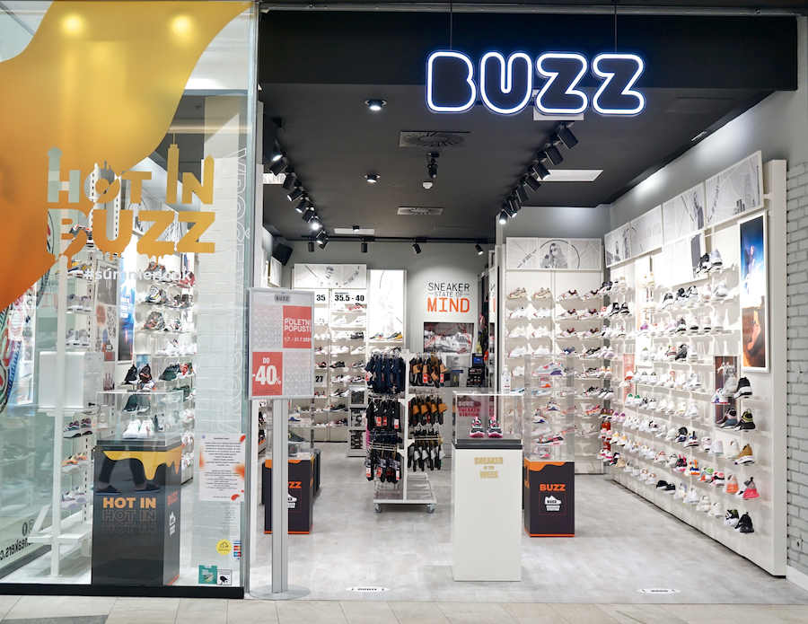 A shoe store named "BUZZ" featuring various sneakers displayed on shelves, with promotional signage visible.