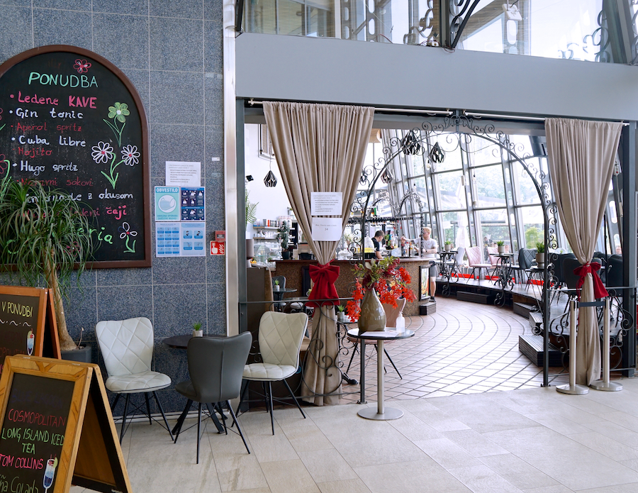 A cozy café entrance with a chalkboard menu, elegant seating, and a view of the bar area through decorative curtains.