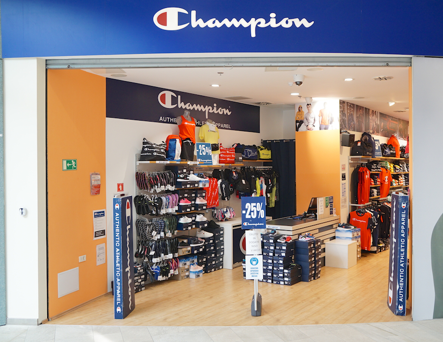 A Champion store entrance featuring athletic apparel, with shelves displaying clothing and accessories, and promotional signage.