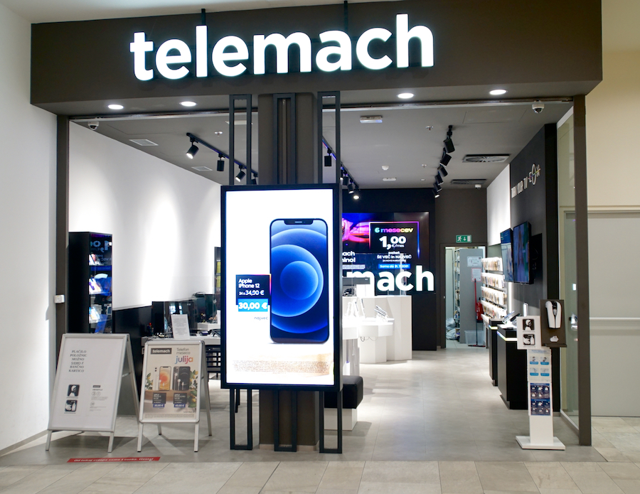 A retail store entrance featuring the "Telemach" logo, a large display with an iPhone advertisement, and product showcases inside.