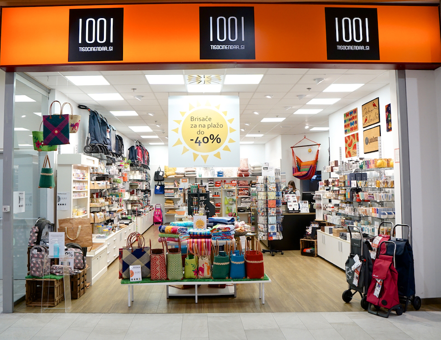 A retail store entrance displaying various bags and home goods, with a promotional sign for discounts.