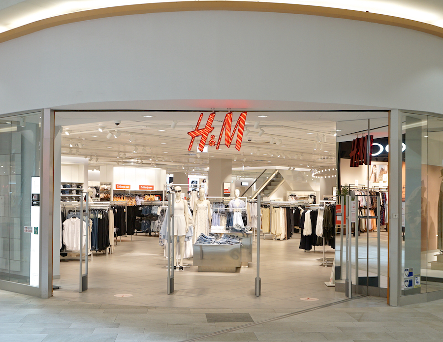 Entrance of an H&M store featuring clothing displays and bright interior lighting.