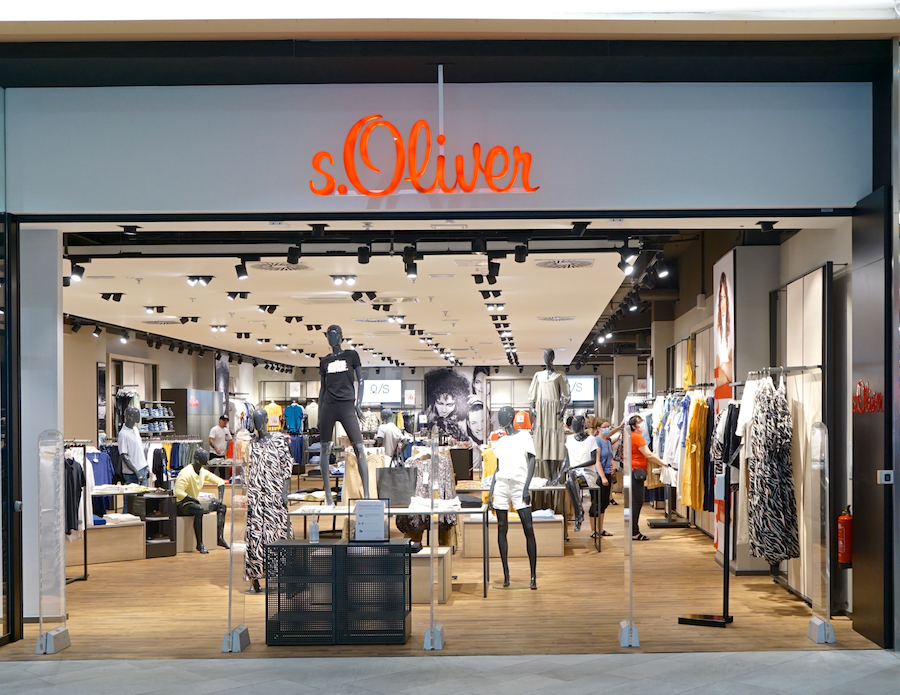 A storefront of s.Oliver featuring mannequins and clothing displays, with shoppers browsing inside.