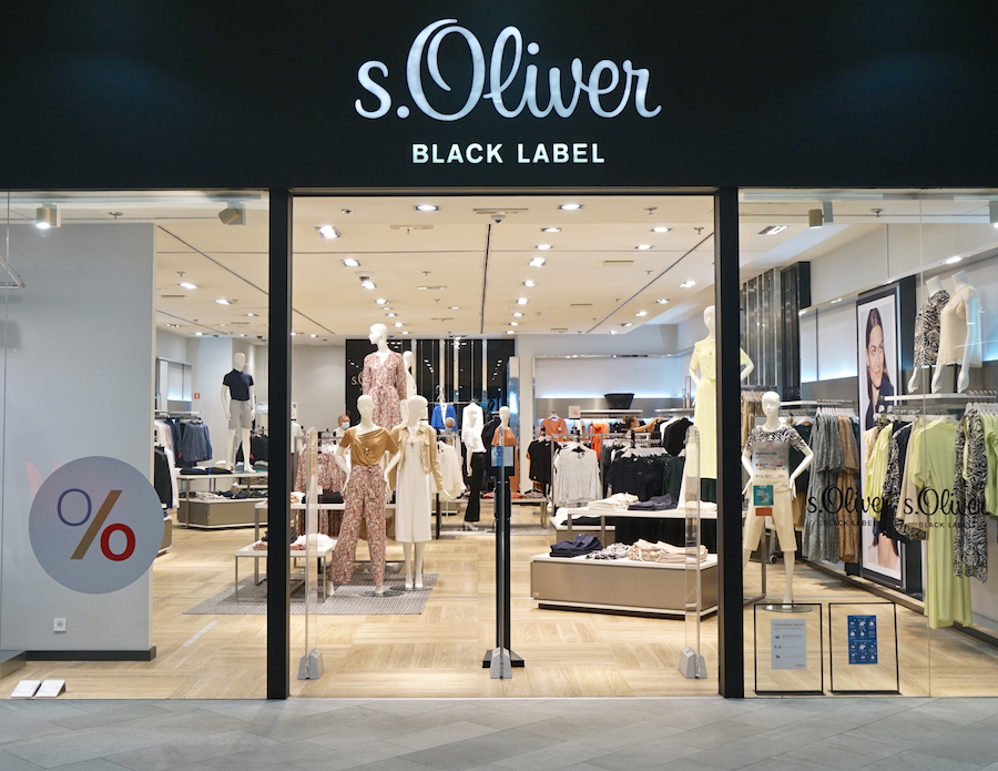 A storefront of s.Oliver Black Label featuring mannequins dressed in various clothing styles and a sale sign.