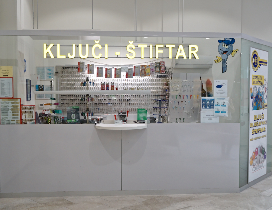 A key shop with a display of various keys and key-related products, featuring a bright sign and a counter for service.