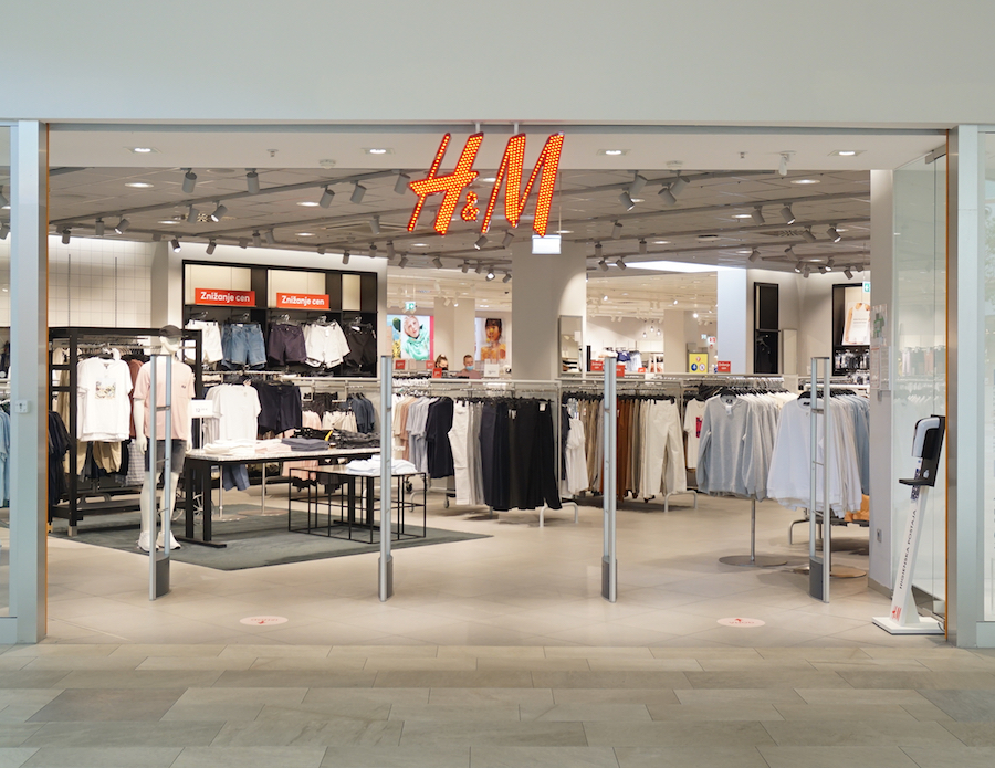 A storefront of H&M featuring clothing racks, mannequins, and bright signage. The interior is well-lit and modern.