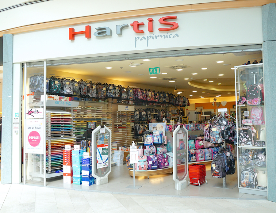 A stationery store entrance featuring colorful backpacks, paper products, and school supplies on display.