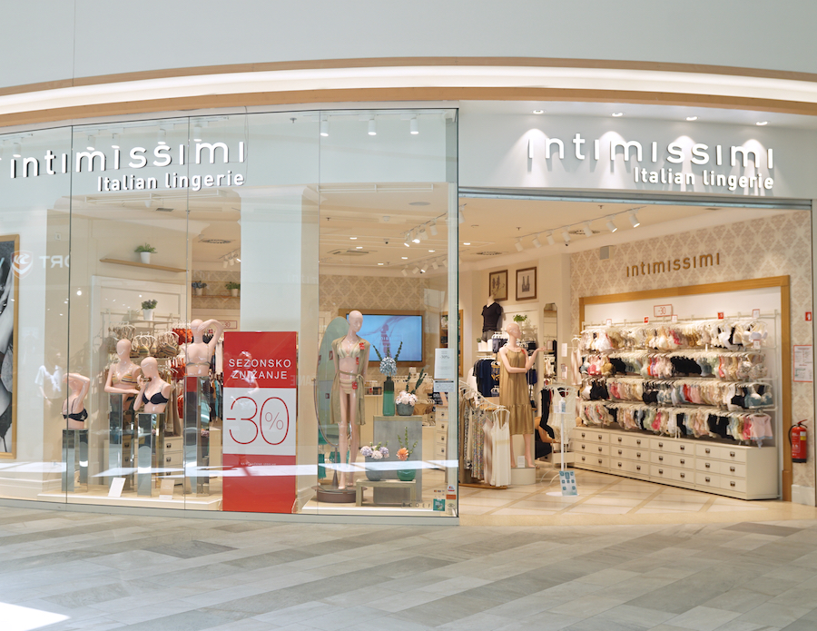 A storefront of Intimissimi, featuring mannequins in lingerie and a seasonal sale sign. The interior displays various lingerie items.