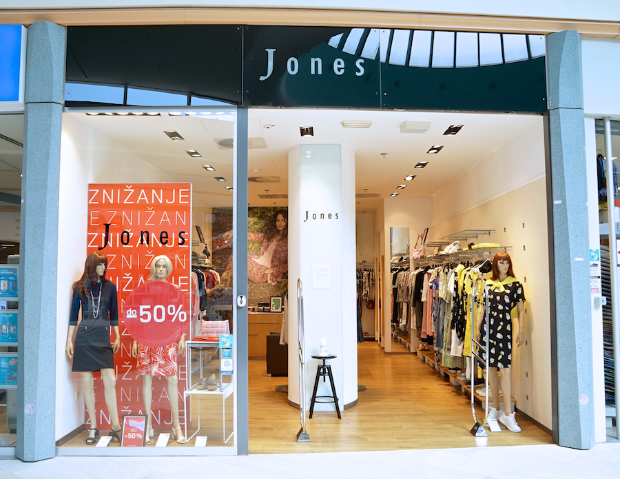 A clothing store entrance featuring mannequins in stylish outfits and a sale sign offering discounts up to 50%.