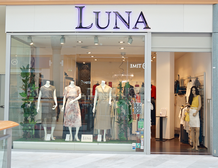 A clothing store named "Luna" featuring mannequins in dresses and a display of various garments inside.