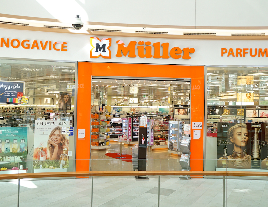 A storefront of Müller, featuring beauty and fragrance products, with bright orange signage and displays inside.