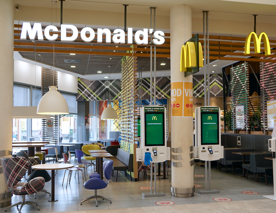 Interior of a McDonald's restaurant featuring self-service kiosks, colorful seating, and modern decor.