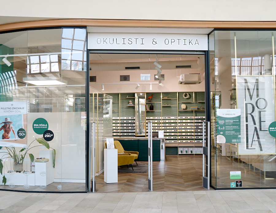 A modern optical store entrance featuring large glass doors, stylish displays of eyewear, and a welcoming interior design.