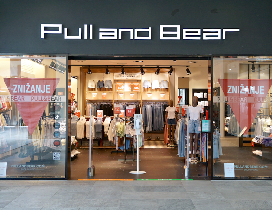 A storefront of Pull and Bear featuring clothing displays, mannequins, and sale signs.