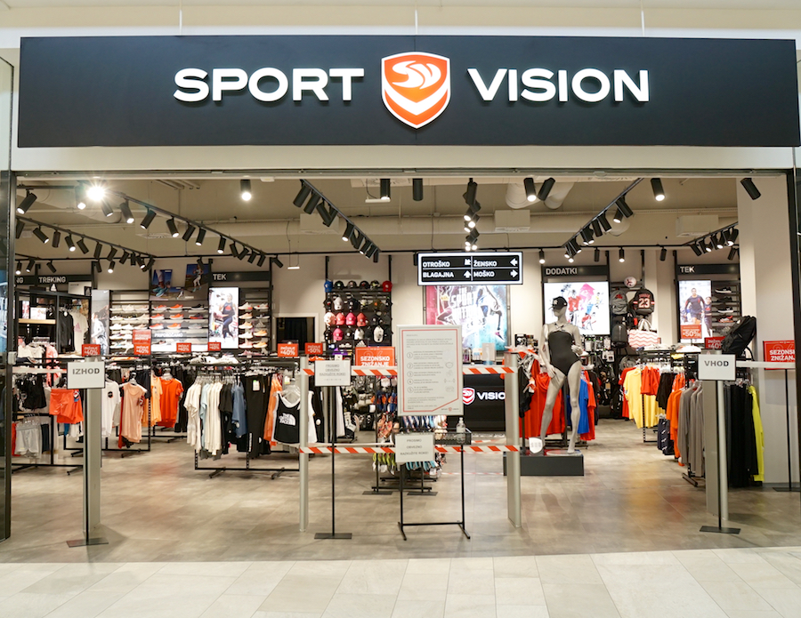 A retail store entrance displaying "Sport Vision" signage, featuring sports apparel and accessories on racks inside.