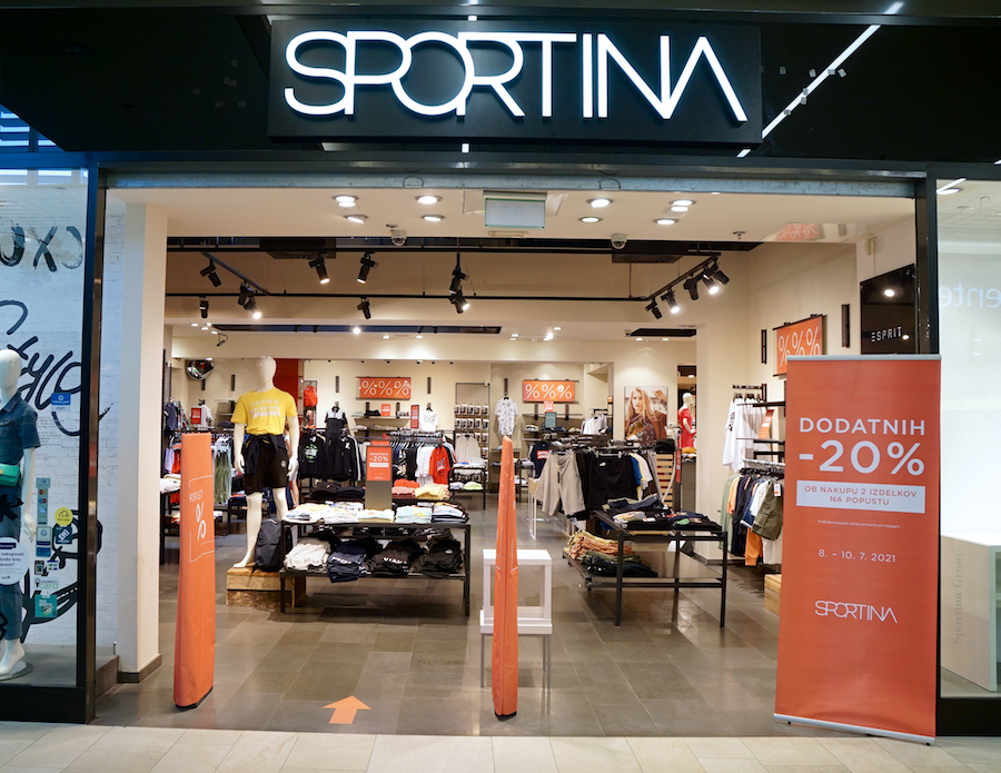 A storefront of "Sportina" featuring clothing displays and promotional signs for discounts.