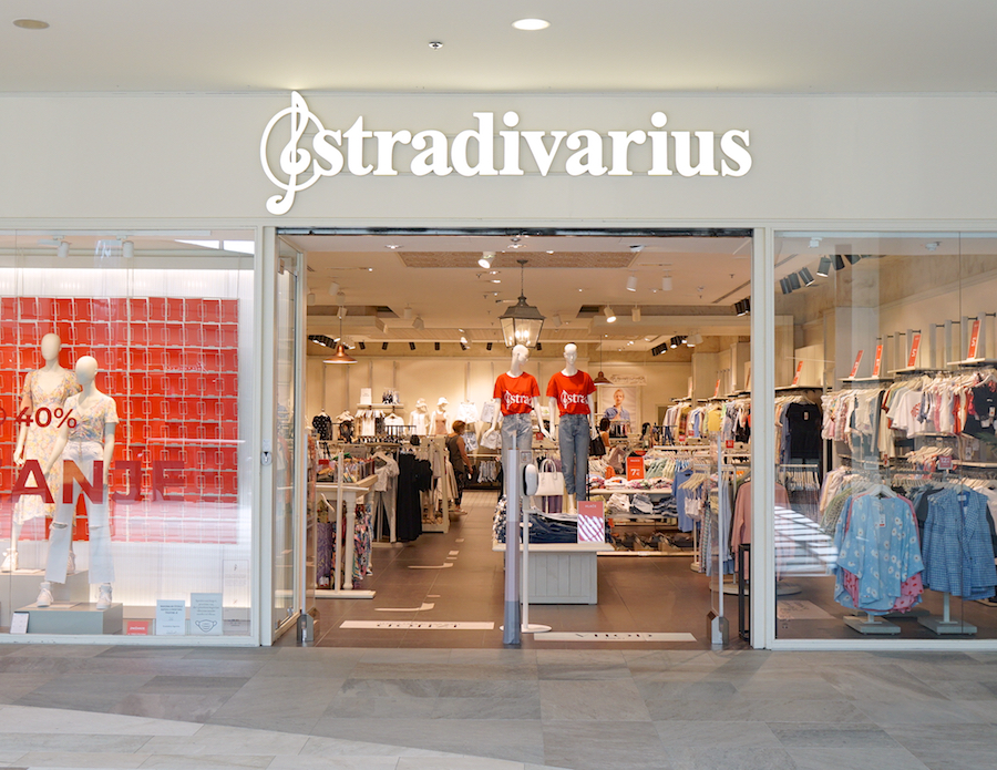 A storefront of Stradivarius featuring mannequins in red shirts and various clothing displays inside.