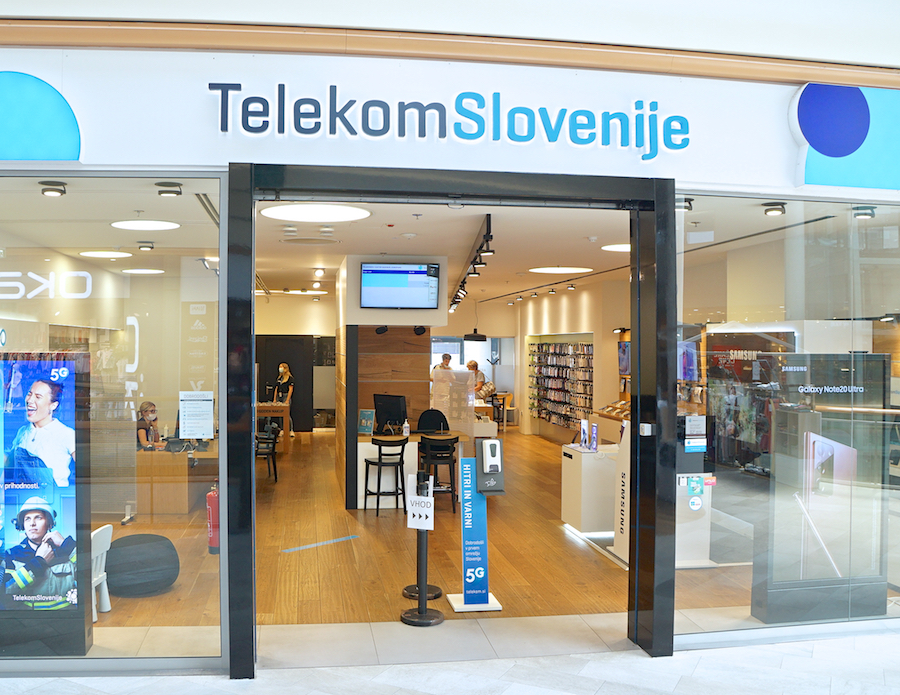 A storefront of Telekom Slovenije featuring a modern interior, displays of mobile devices, and promotional signage for 5G services.