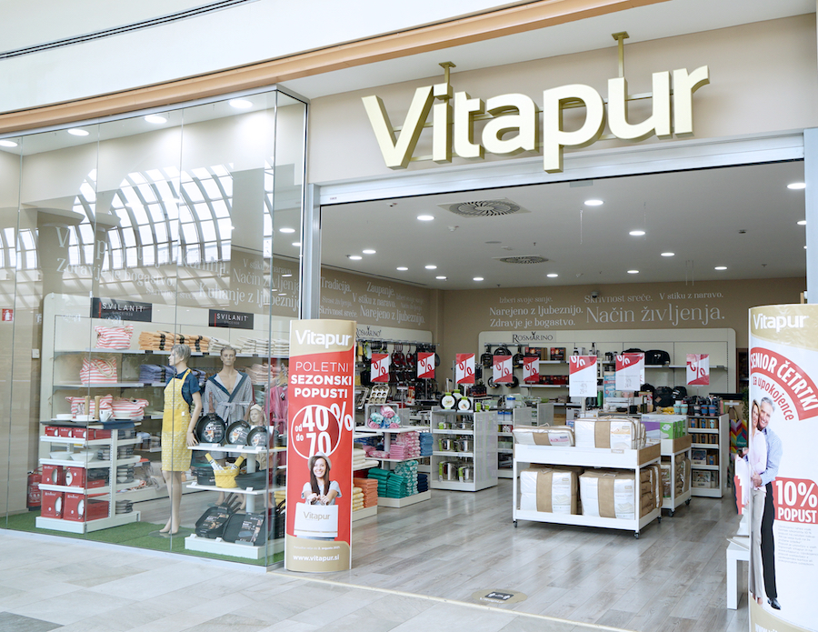 A storefront of Vitapur featuring home goods, textiles, and promotional signs for seasonal discounts.