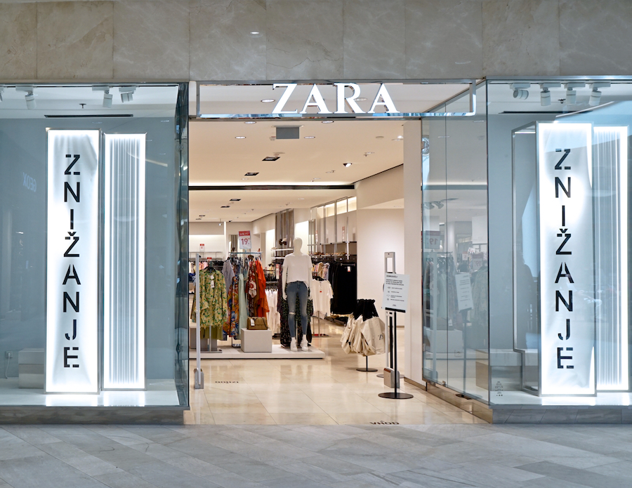 A Zara store entrance featuring illuminated signage and a display of clothing inside.