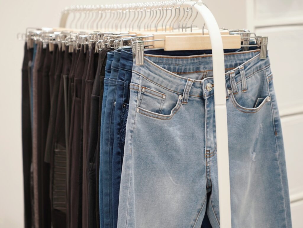 A rack displaying various styles of jeans, including light blue, dark blue, and black options, hanging neatly.