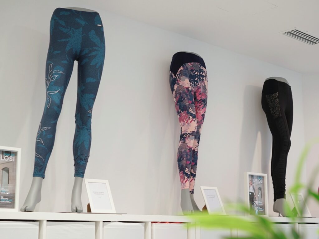 Three pairs of leggings displayed on mannequins against a white wall, featuring various patterns and colors.